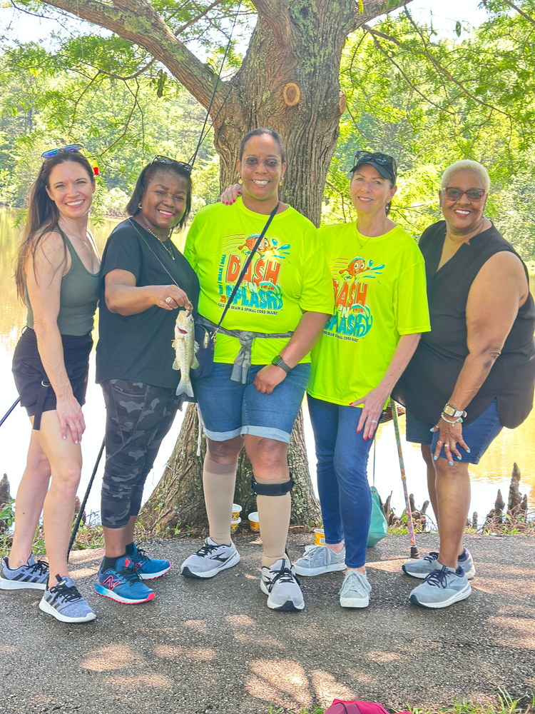 A group of women are standing next to each other holding fishing rods and a fish.