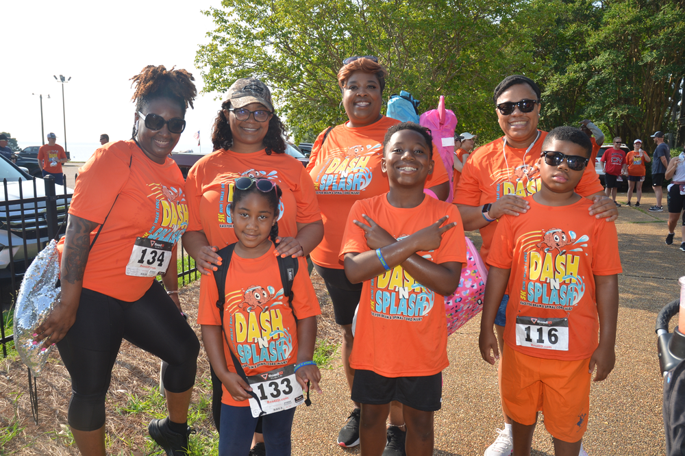 A group of people wearing orange shirts are posing for a picture.