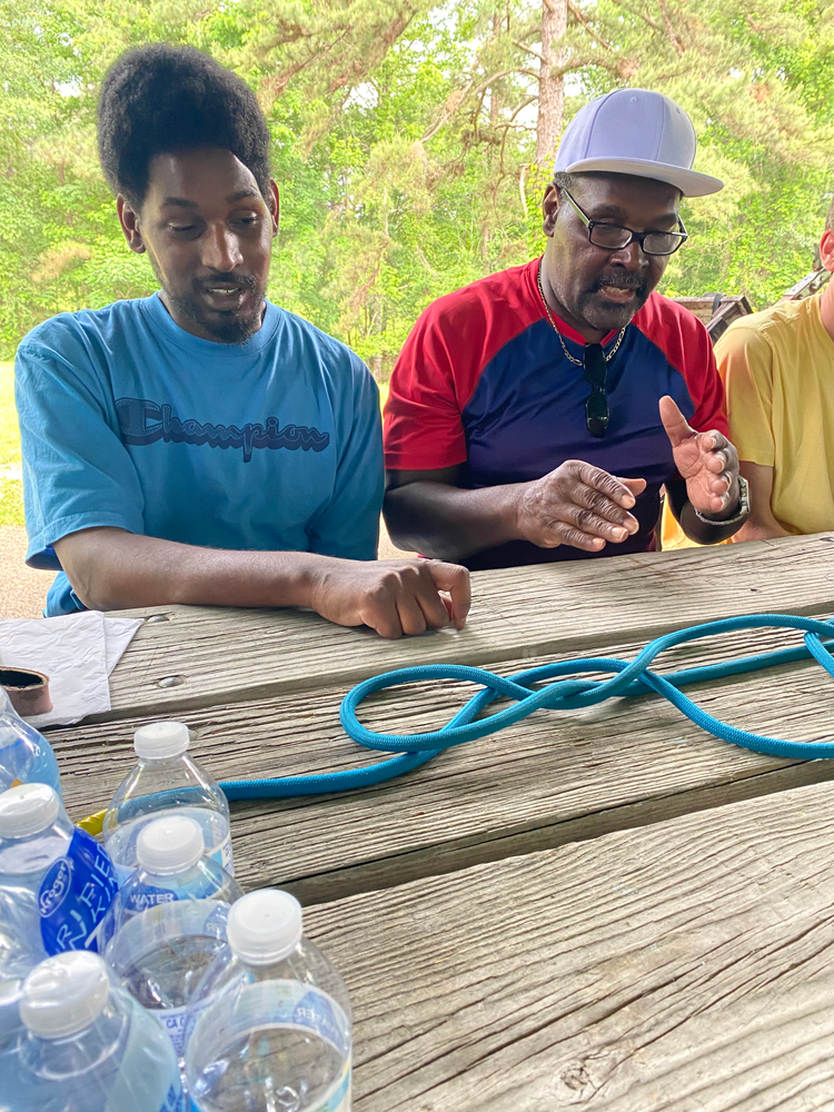 A group of men are sitting at a picnic table with water bottles.