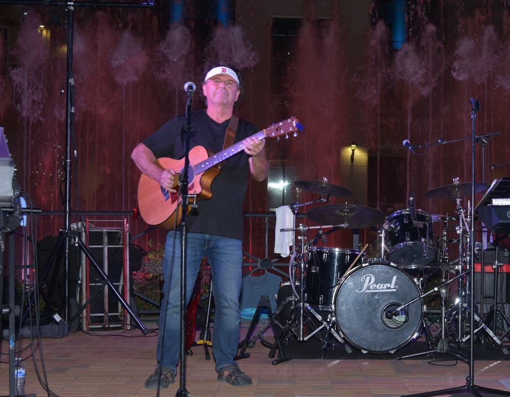 A man playing a guitar in front of a pearl drum set