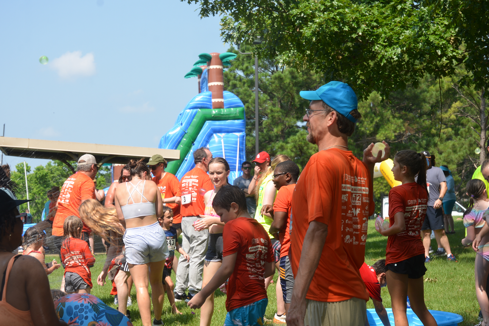 A group of people are standing in a park with a bouncy house in the background.