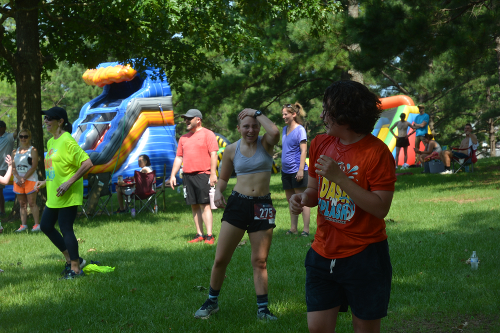 A group of people are standing in a park with a bouncy house in the background.