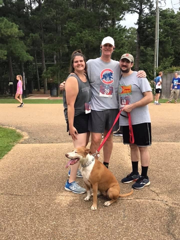 A group of people standing next to a dog on a leash.