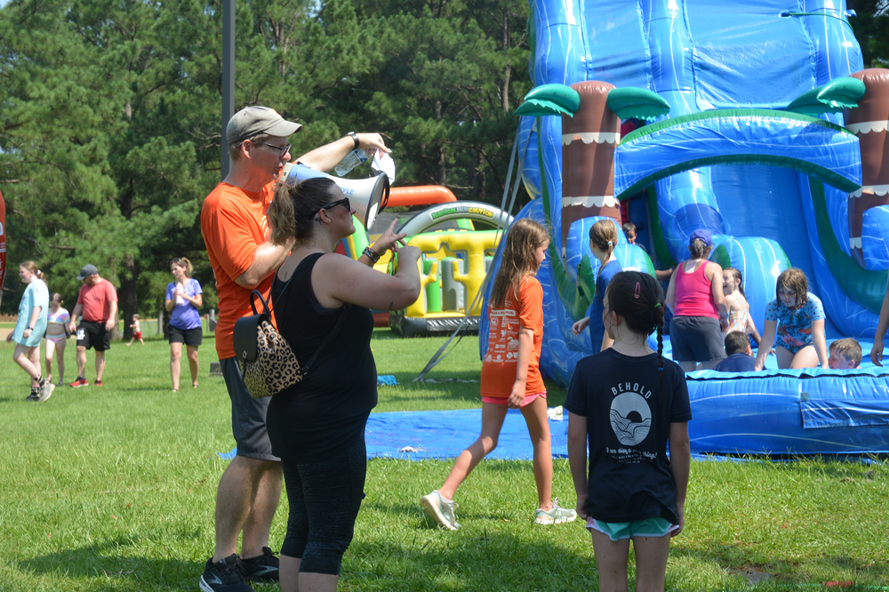 A group of people are standing in front of a bouncy house.