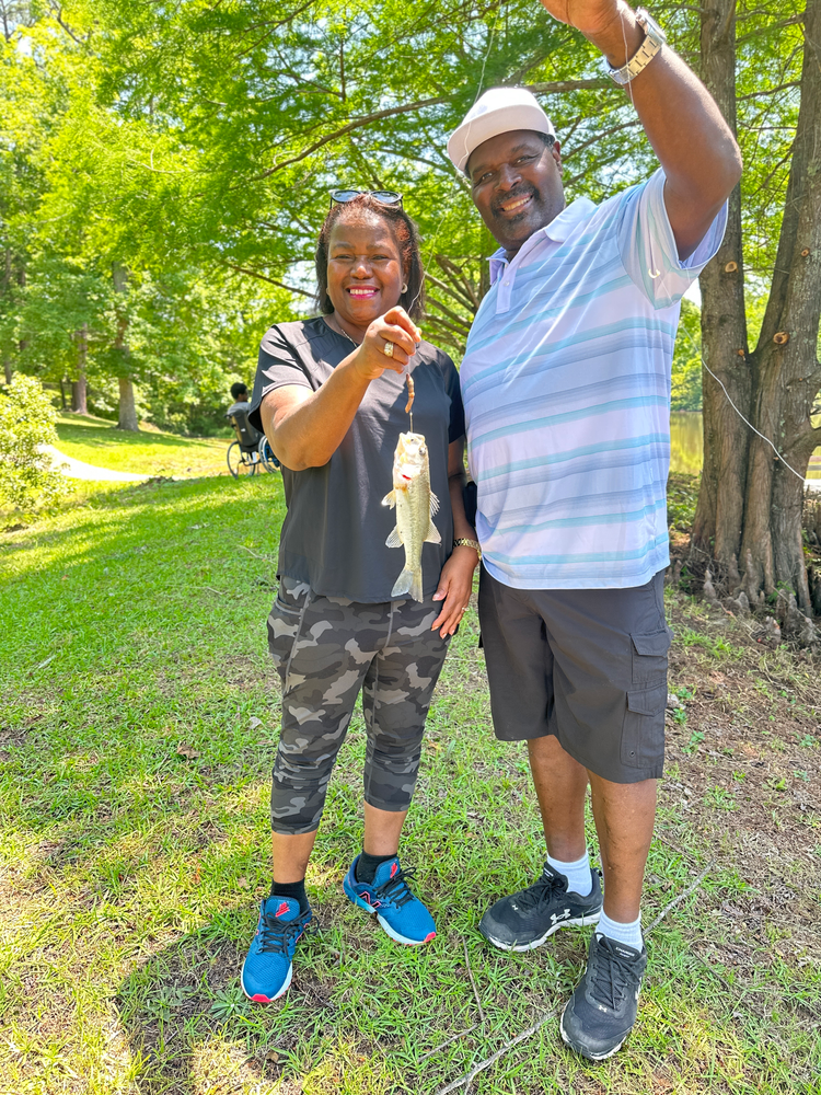 A man and a woman are standing next to each other holding a fish.