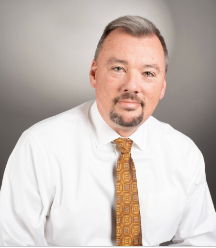 A man with a beard wearing a white shirt and tie