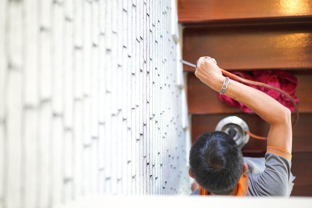 A Man Is Cleaning A Wall With A Vacuum Cleaner — Maximum Pest Management In Atherton, QLD
