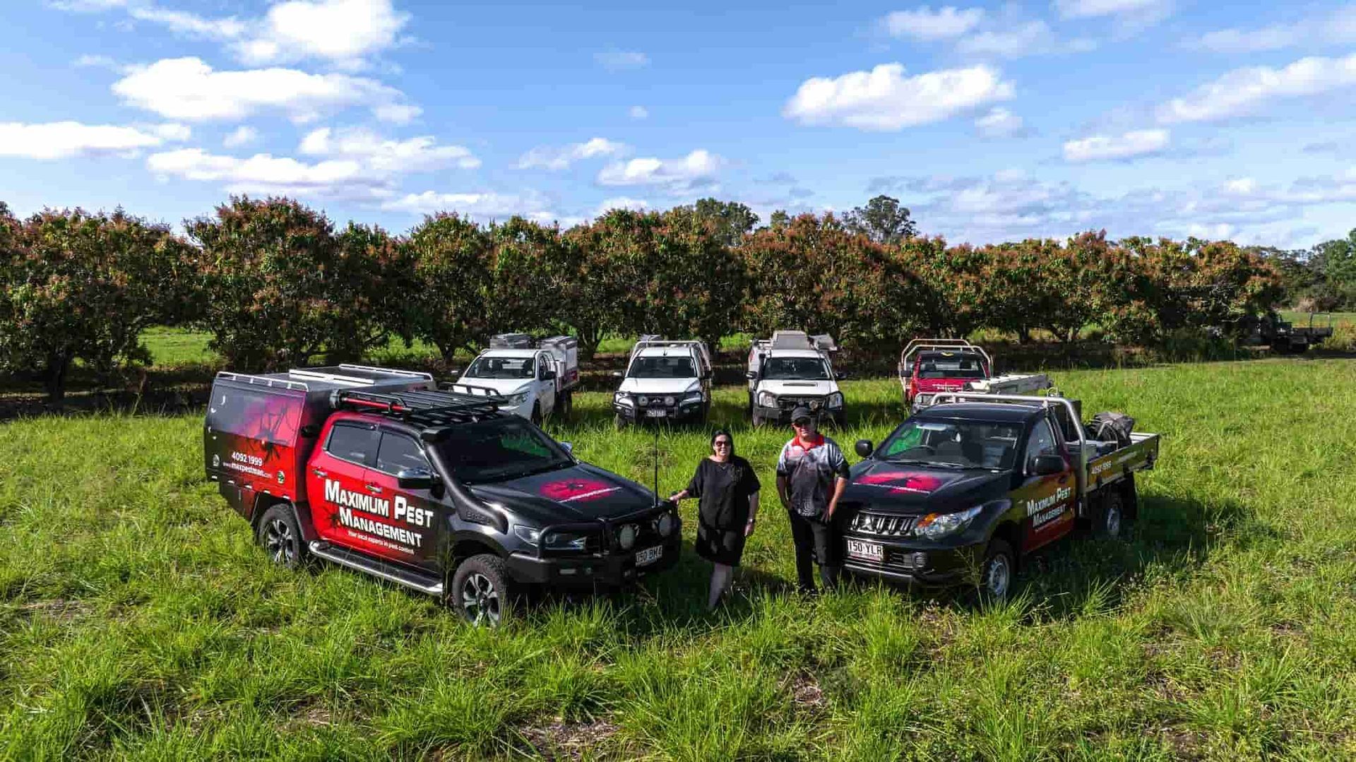 A Group Of Trucks Are Parked In A Grassy Field — Maximum Pest Management In Mareeba, QLD