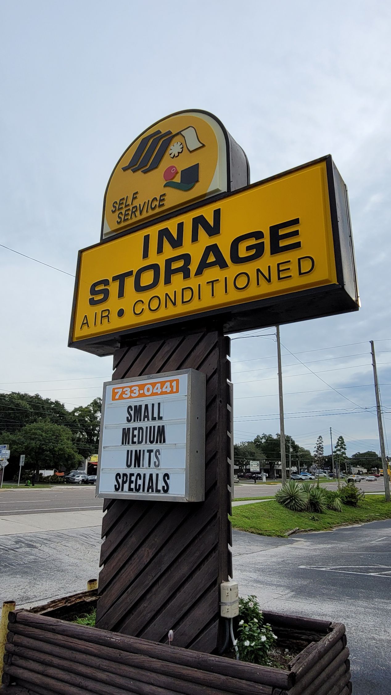 Yellow Inn Storage roadside sign in a parking lot, with a smaller handwritten notice below.