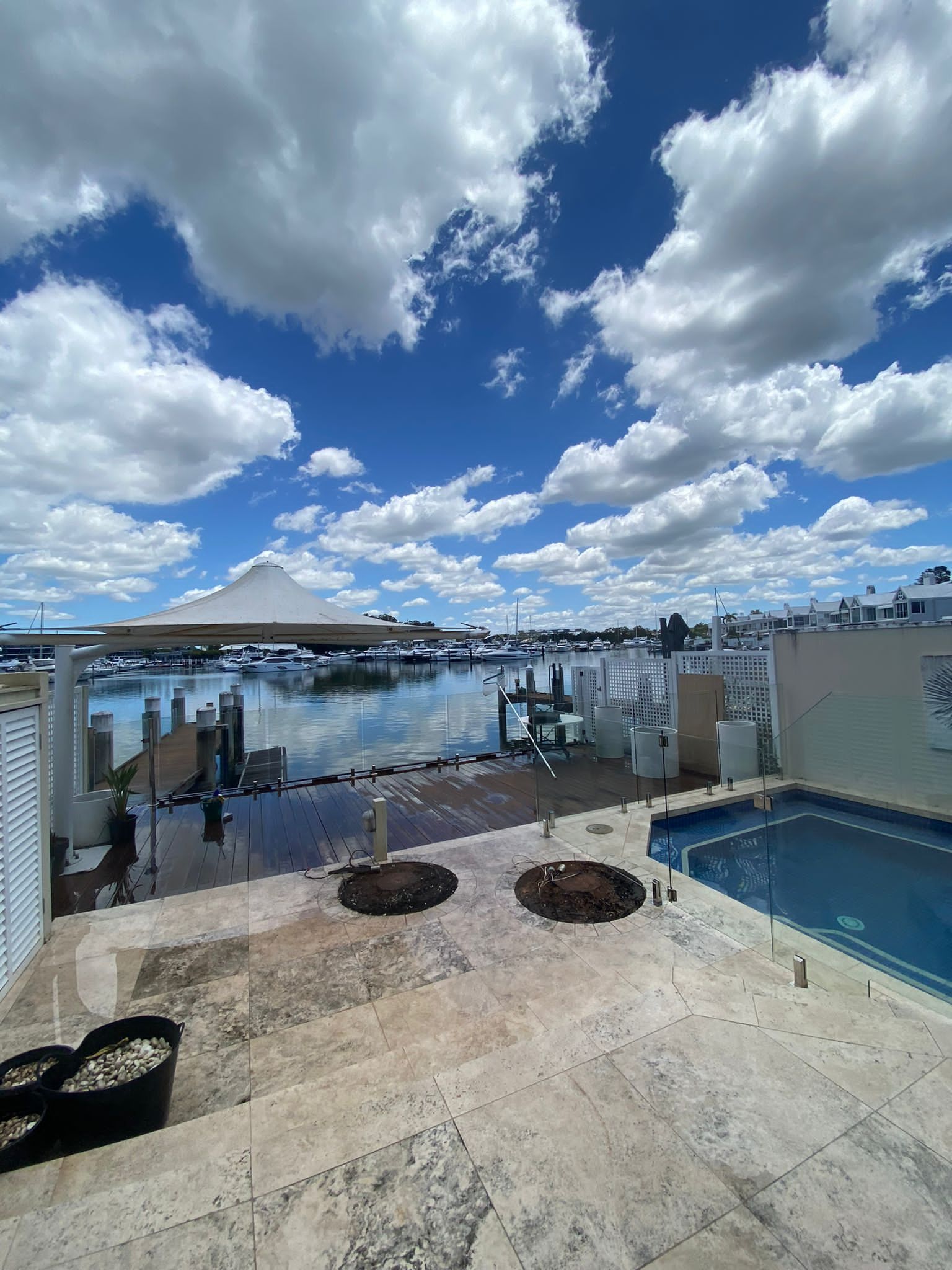 Waterfront patio with pool, docked boats, and dramatic cloudy sky over the marina.