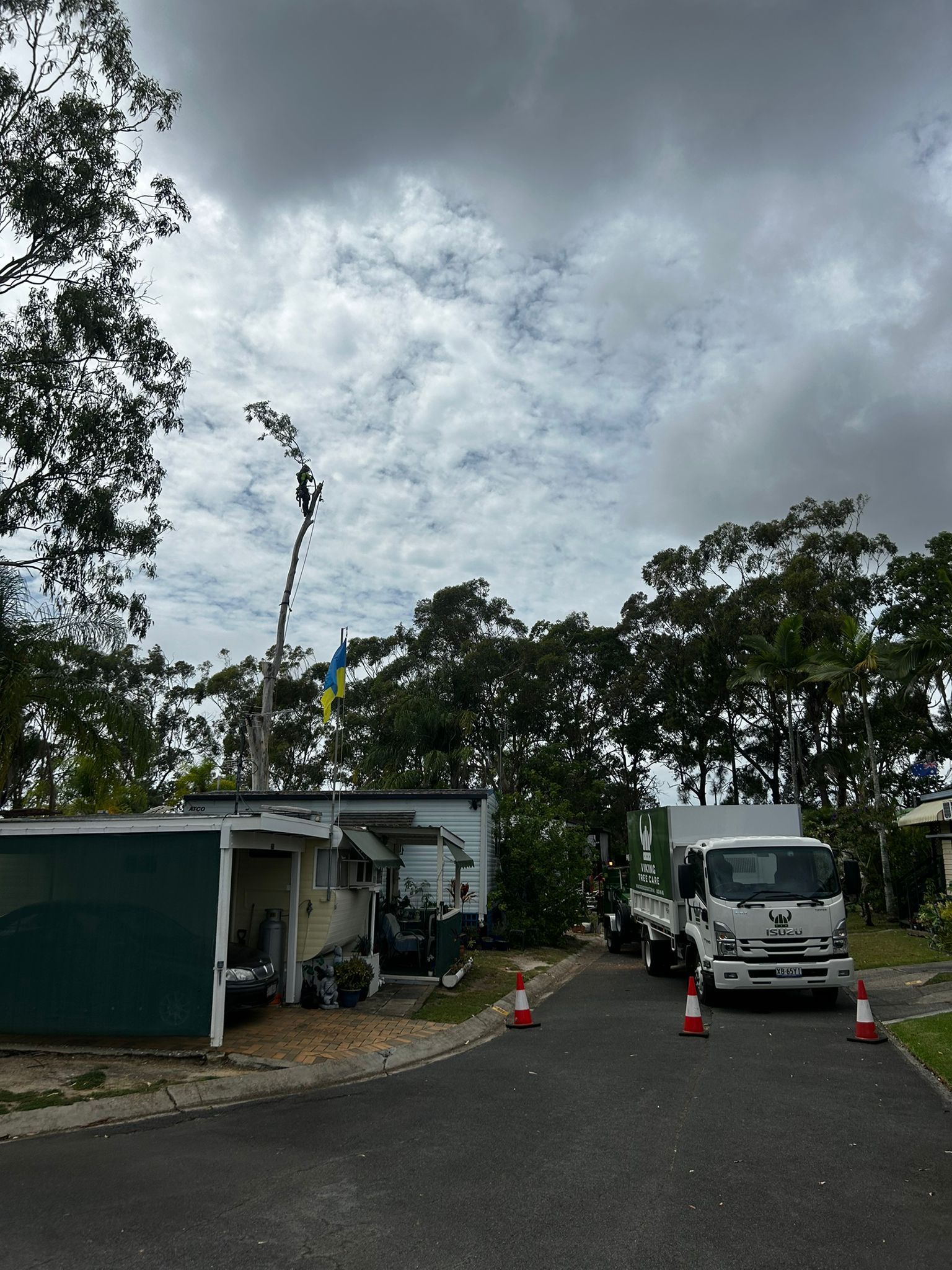 Truck parked on a cloudy roadside beside small buildings and orange traffic cones