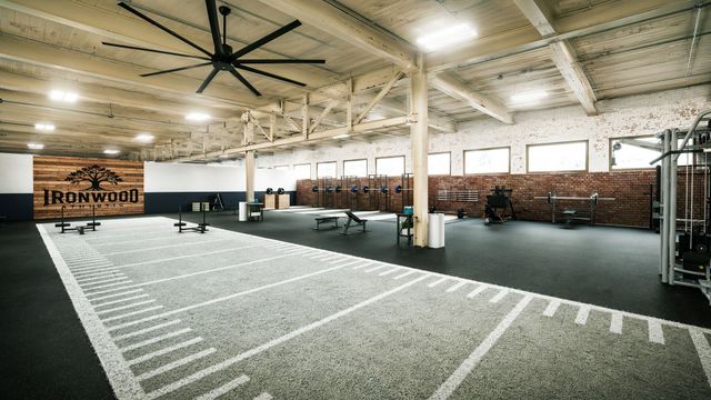 Empty indoor sports hall with high ceilings, track lanes, and benches under bright overhead lights
