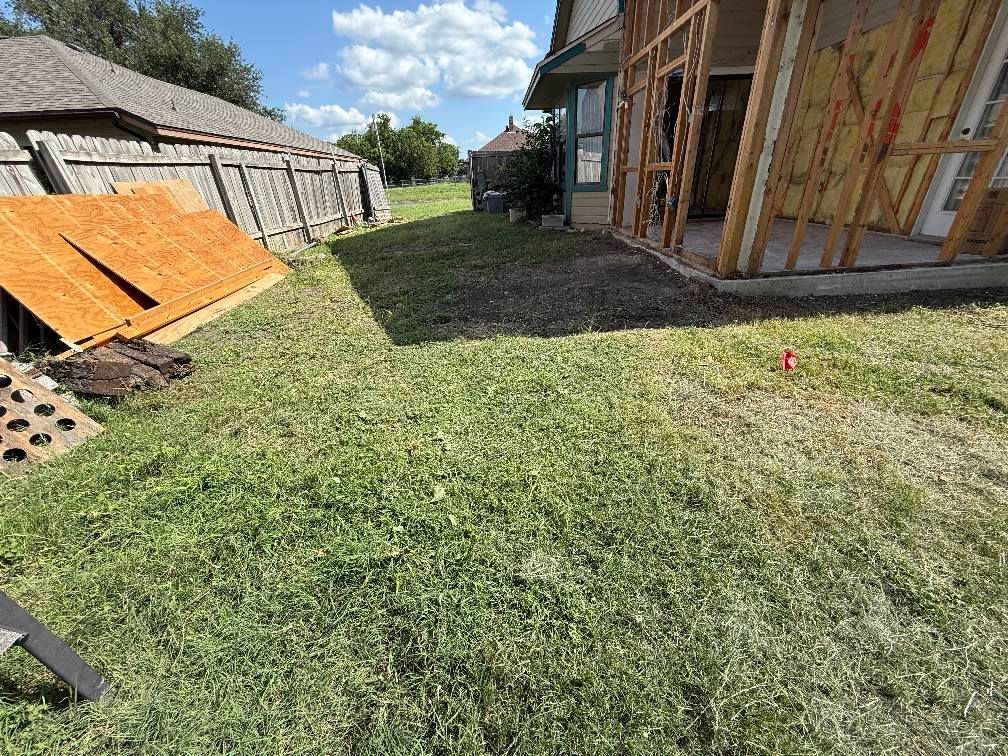 A house is being built in a backyard with a lot of grass.