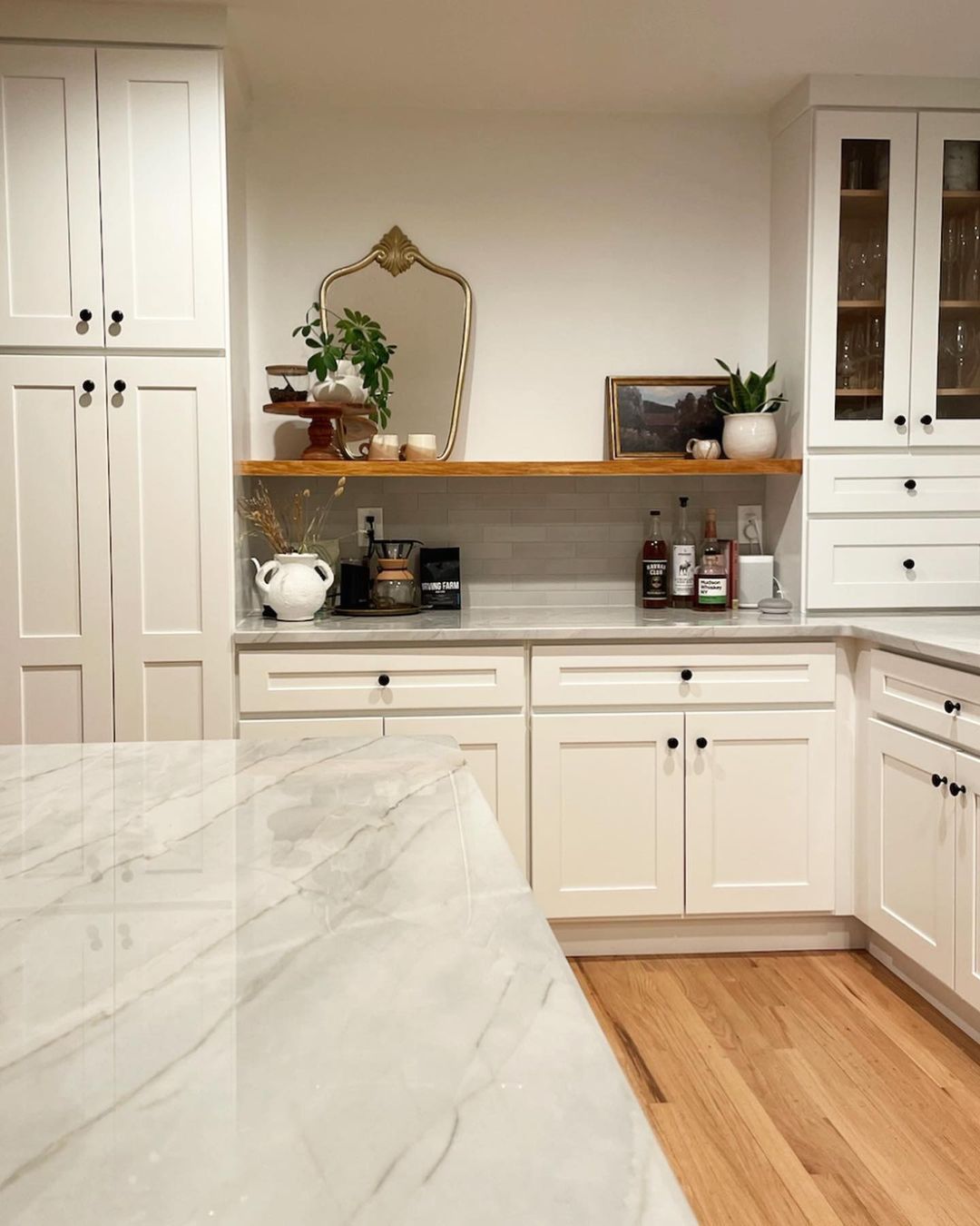 A kitchen with white cabinets and marble counter tops