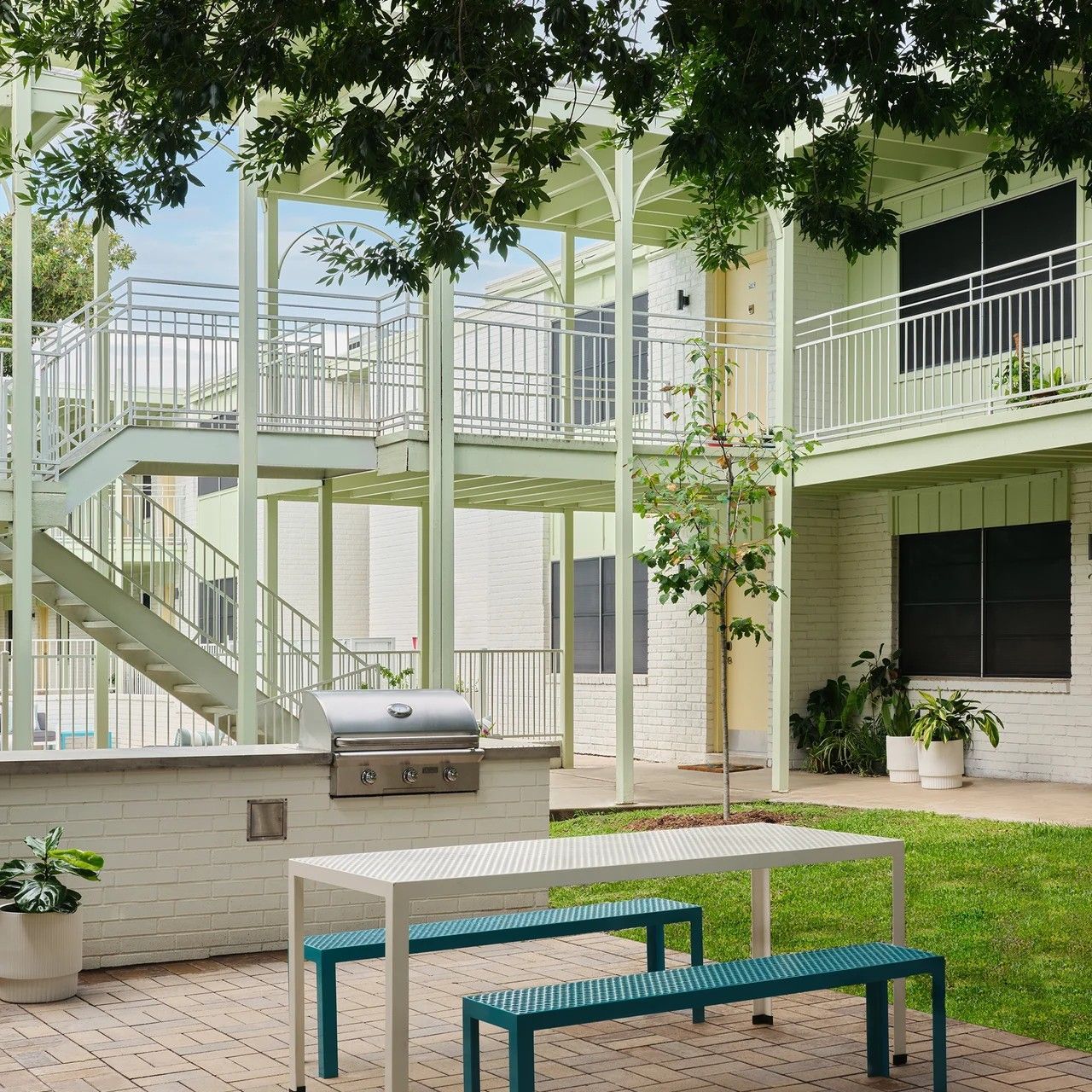 A white table with blue benches in front of a building