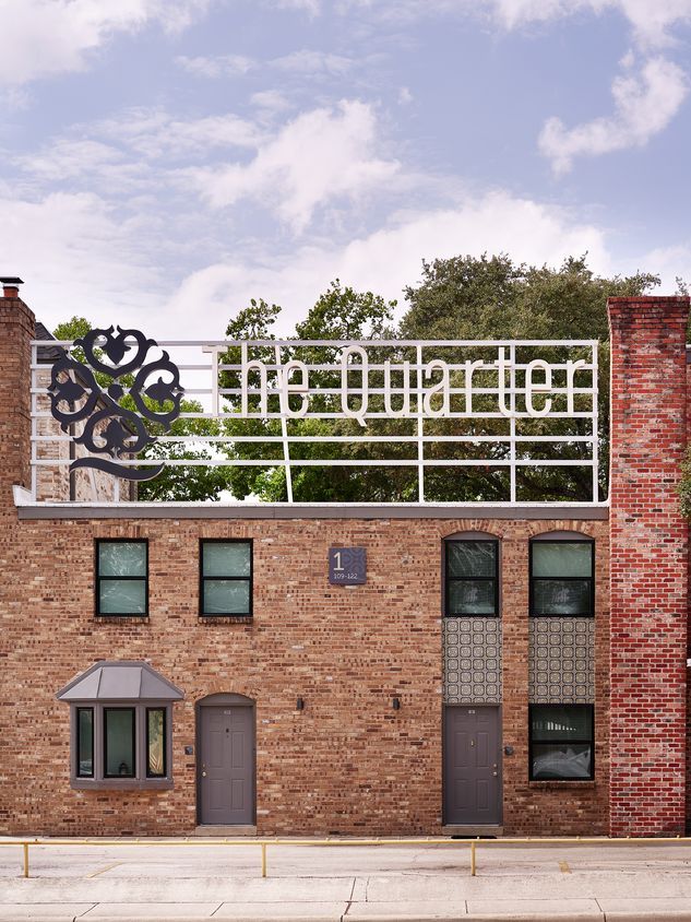 A brick building with a sign on top that says the quartier