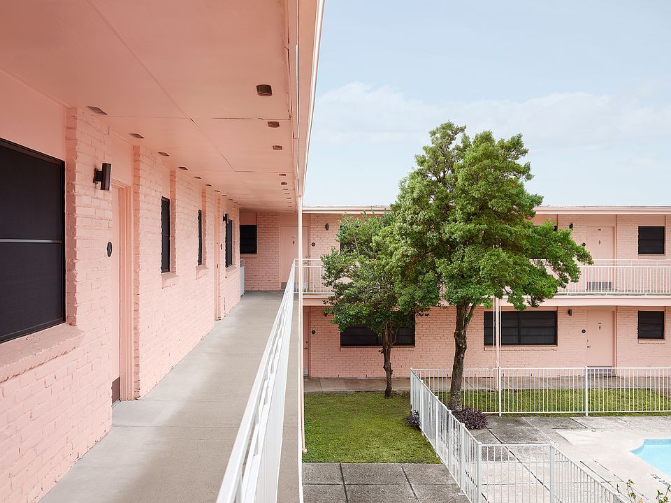 A pink apartment building with a swimming pool in the backyard