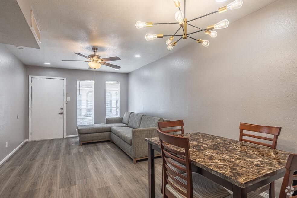 A living room with a couch , table and chairs and a ceiling fan.