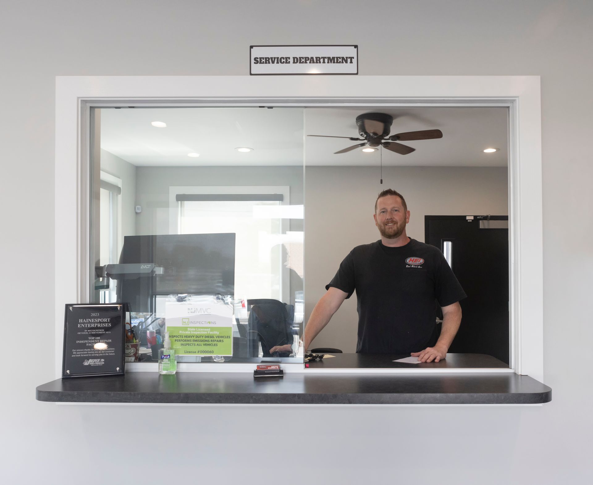 Man standing at a service counter behind a window labeled
