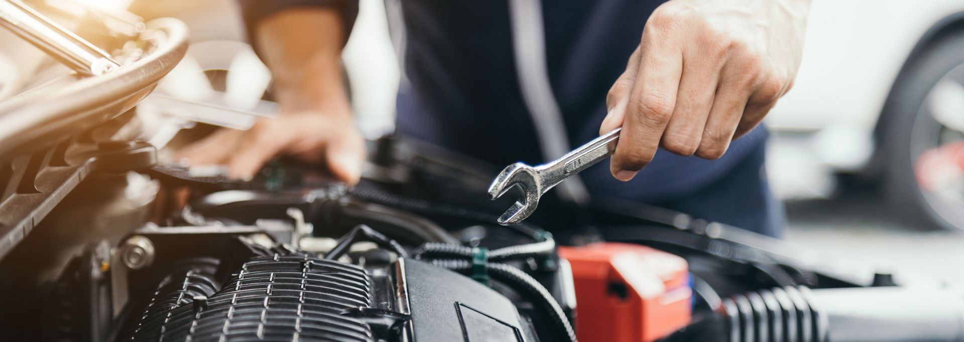 A person repairing a car engine with a wrench.