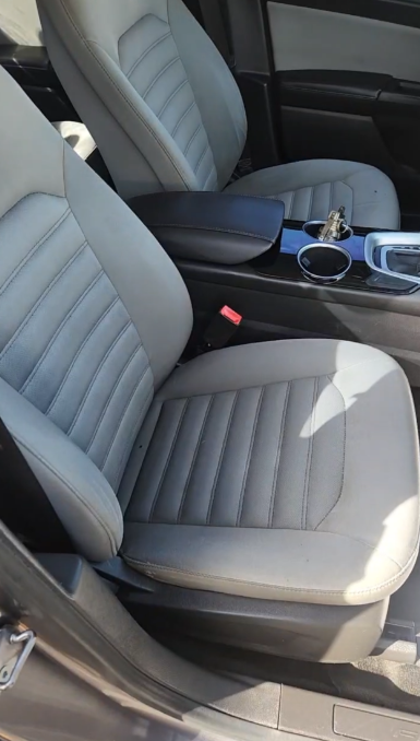 Gray and black car seats, interior view with armrest, cup holder, and keys.