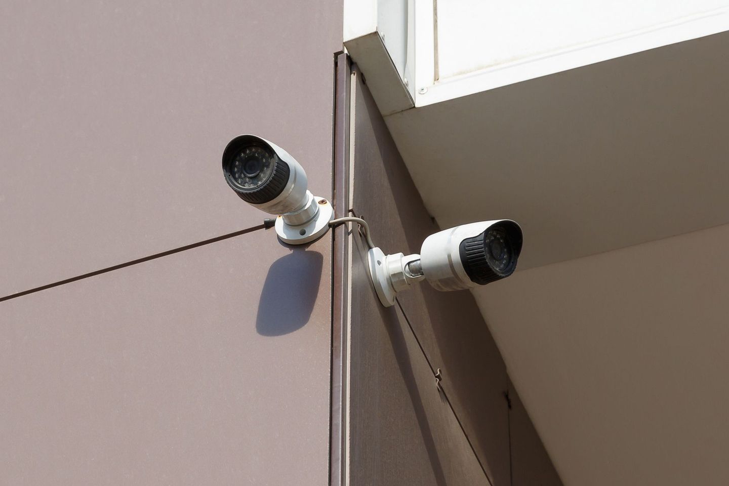 Due telecamere di sicurezza bianche montate sull'angolo di un edificio.