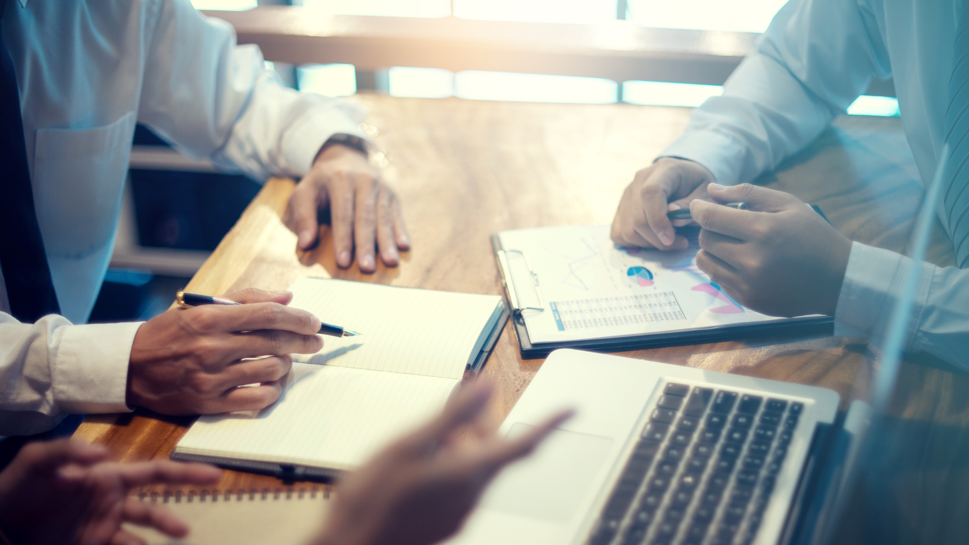 Business meeting with hands over documents and laptop on a conference table