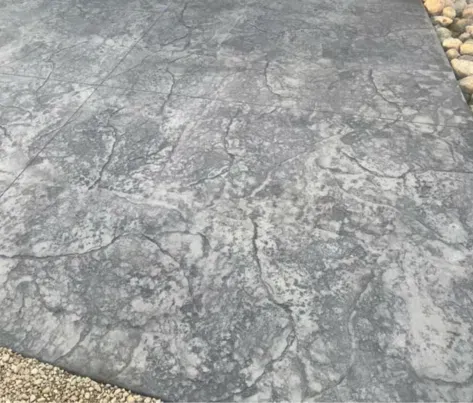 Gray concrete patio with a mottled, marbled texture next to gravel edging