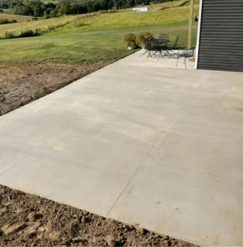 Concrete patio beside a house overlooking a grassy yard and hills