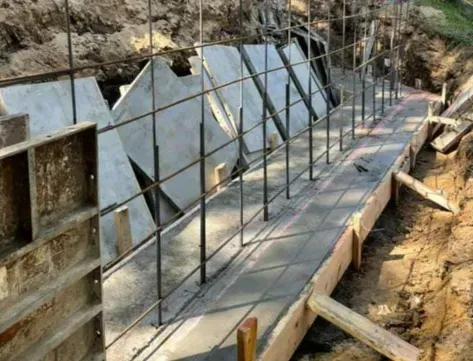 Concrete foundation under construction with steel rebar and formwork along a trench