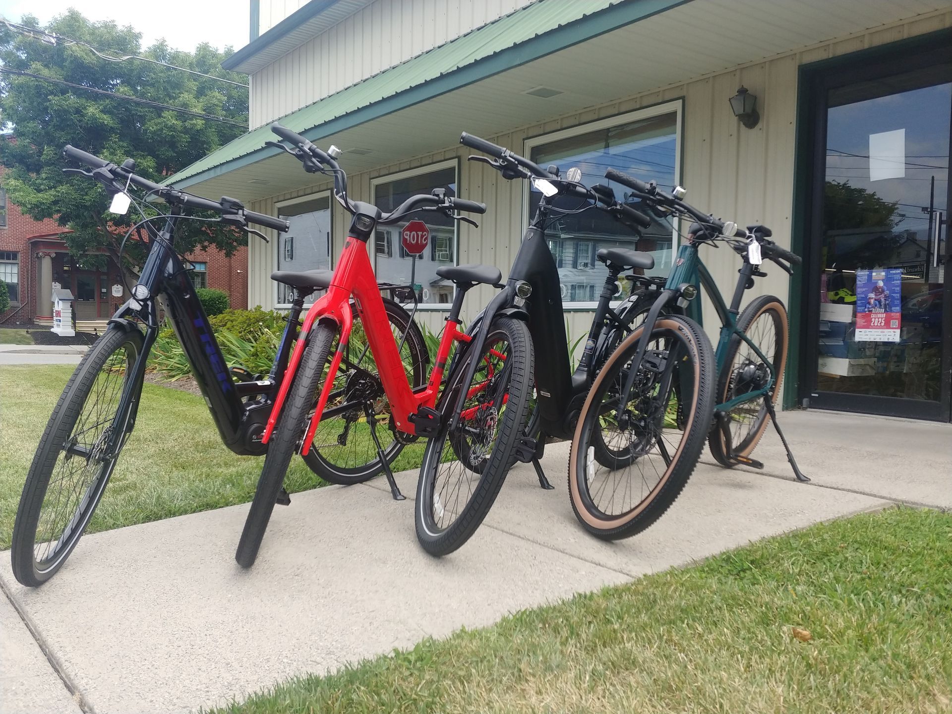 Several bicycles parked outside a building entrance on a sidewalk, including red and black bikes.