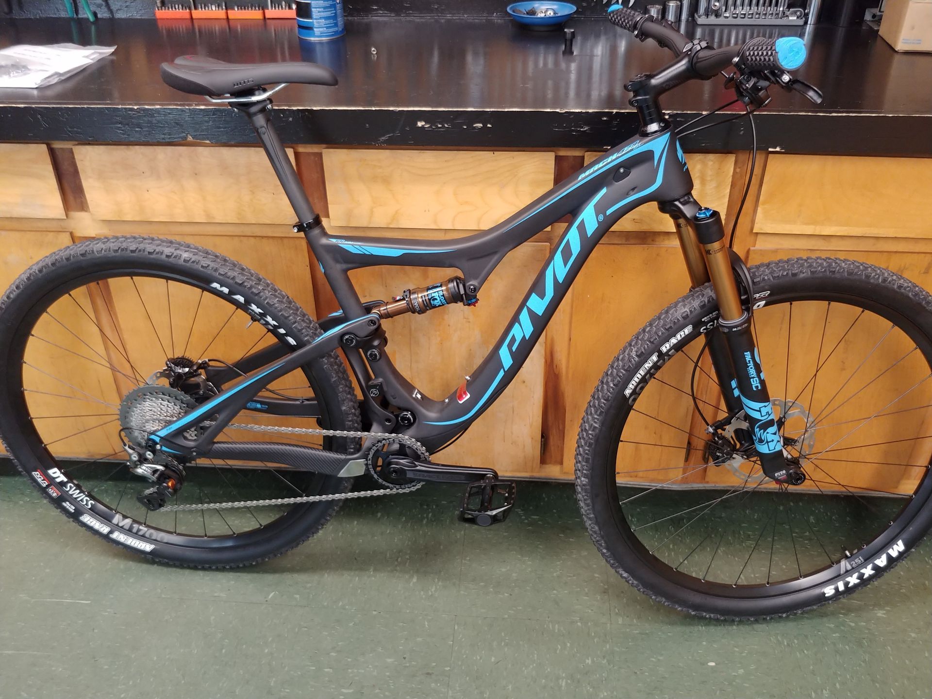 Black and blue mountain bike leaning against a workbench in a garage