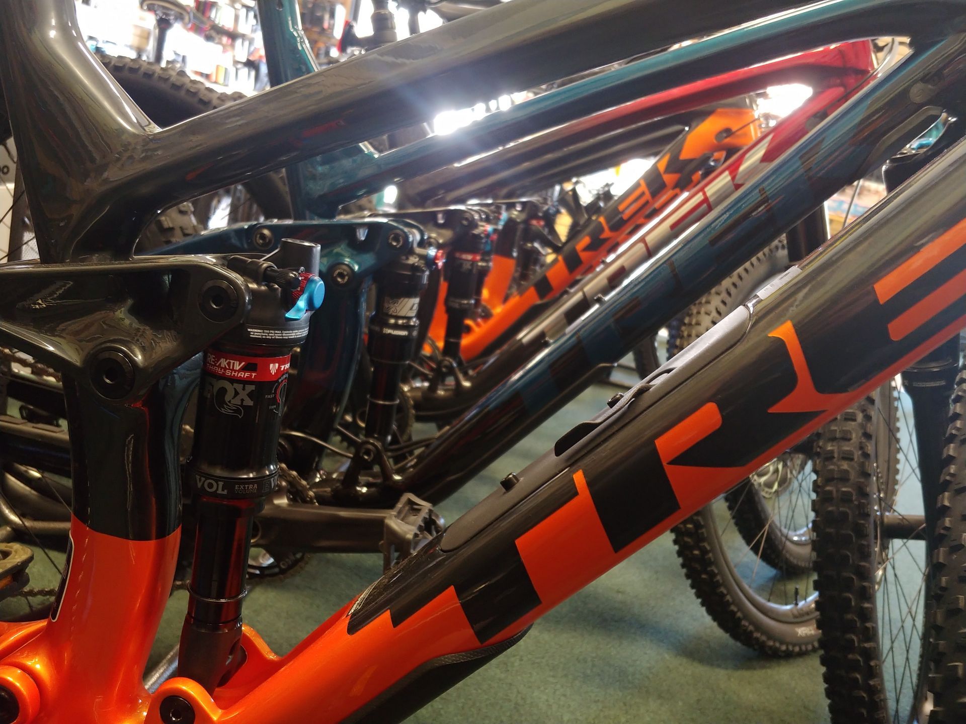 Close-up of an orange and black Trek mountain bike frame and rear suspension indoors.