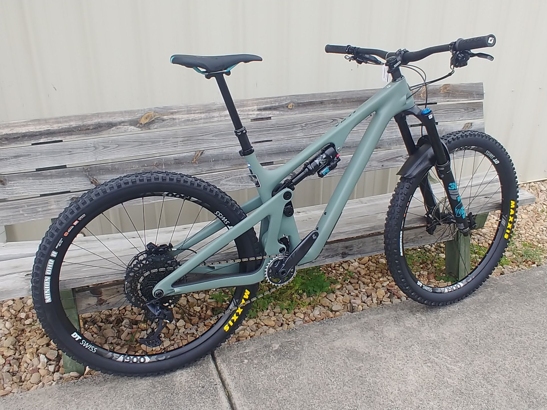 Mint-green mountain bike parked against a stone wall outdoors