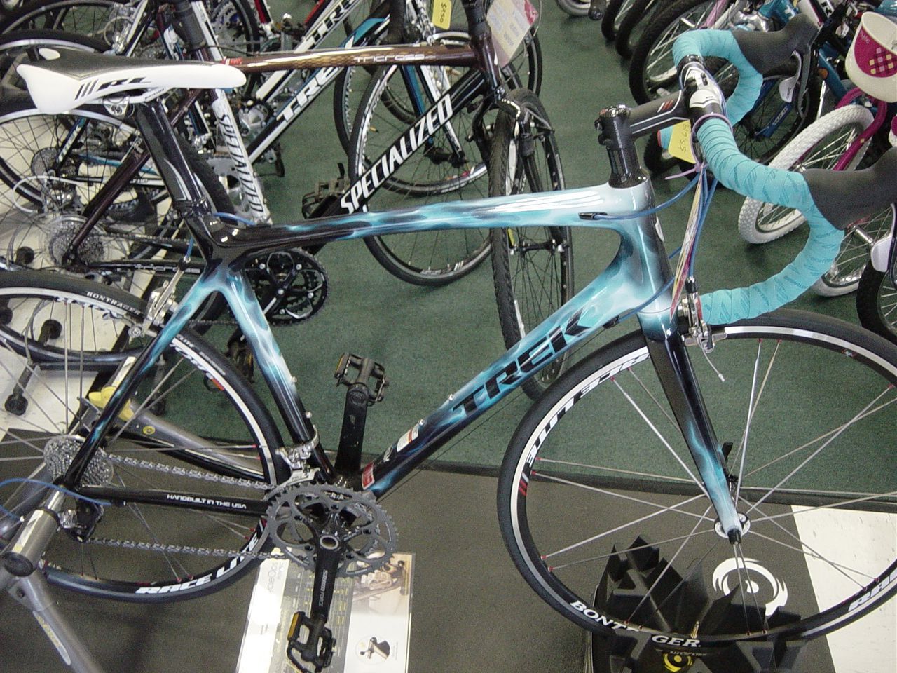 Blue-and-black road bike parked among other bicycles in a crowded rack