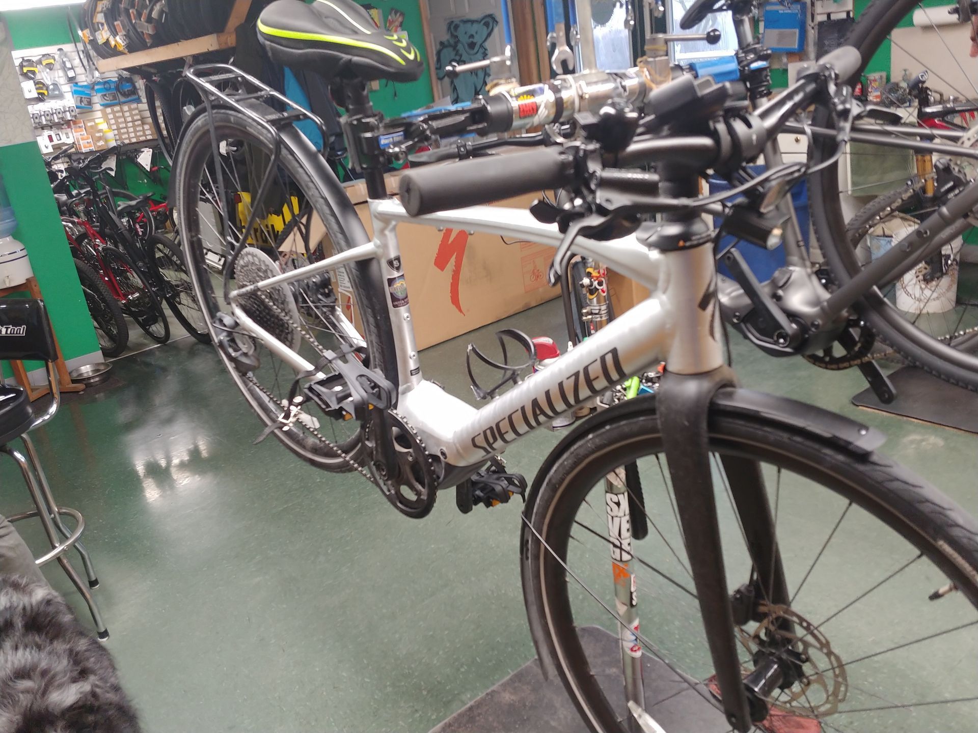Specialized road bike in a bicycle shop, with other bikes and tools in the background.