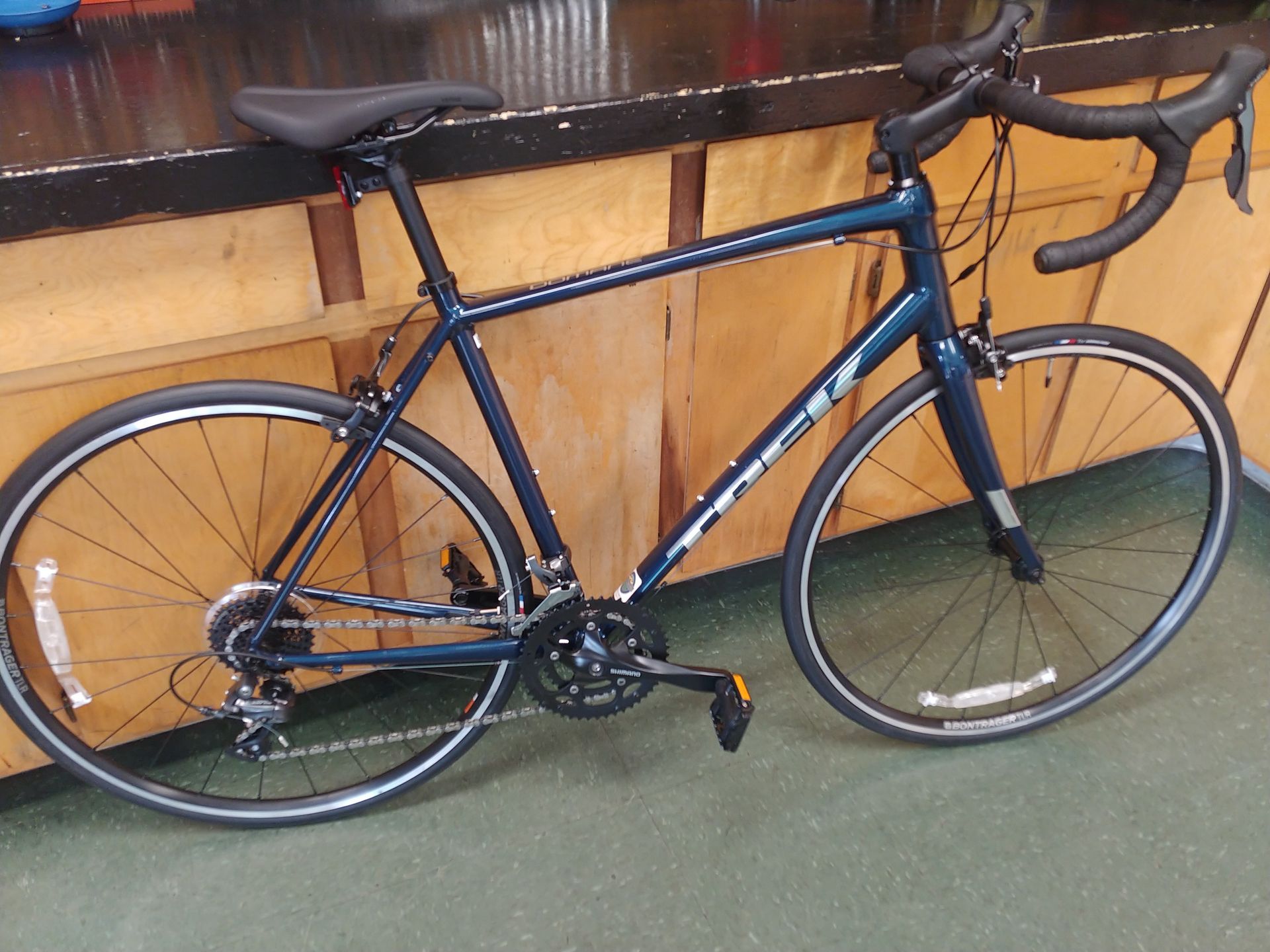 Blue road bike leaning against a wooden wall indoors