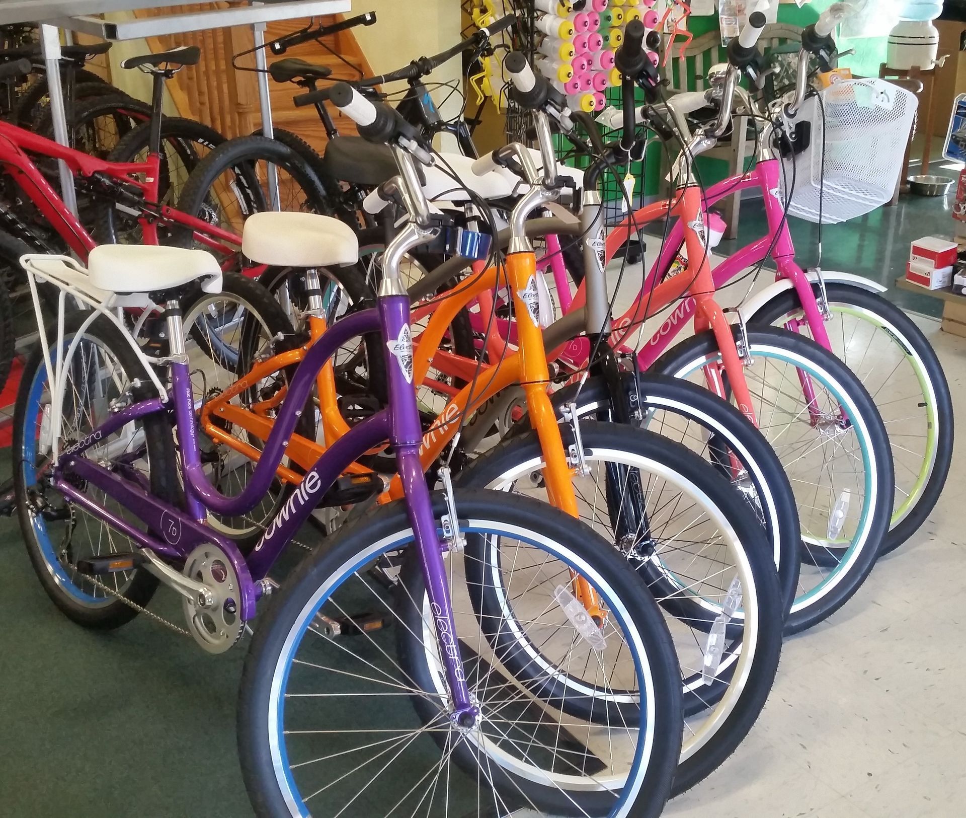 Colorful bicycles lined up in a shop, with purple, orange, and pink bikes in the foreground.