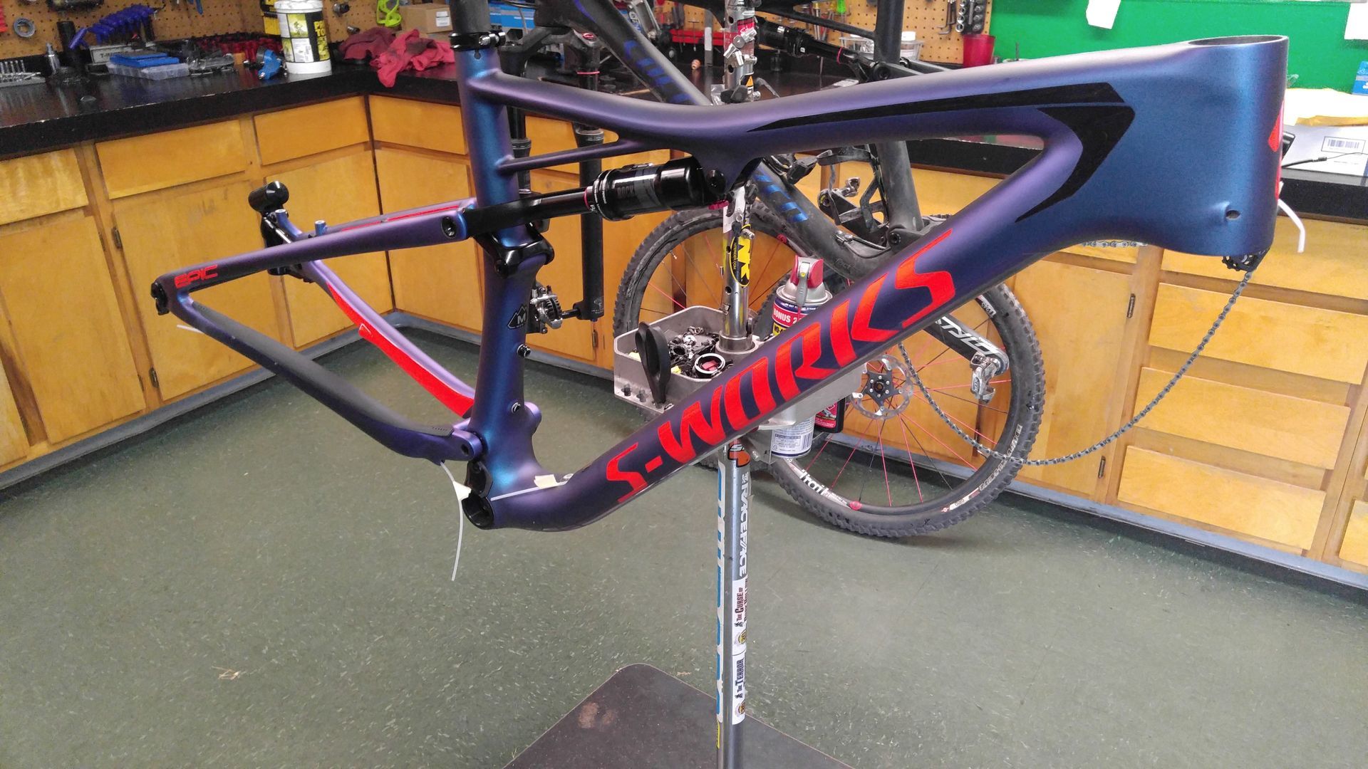 Specialized road bike on indoor stand, black with red accents in a workshop.