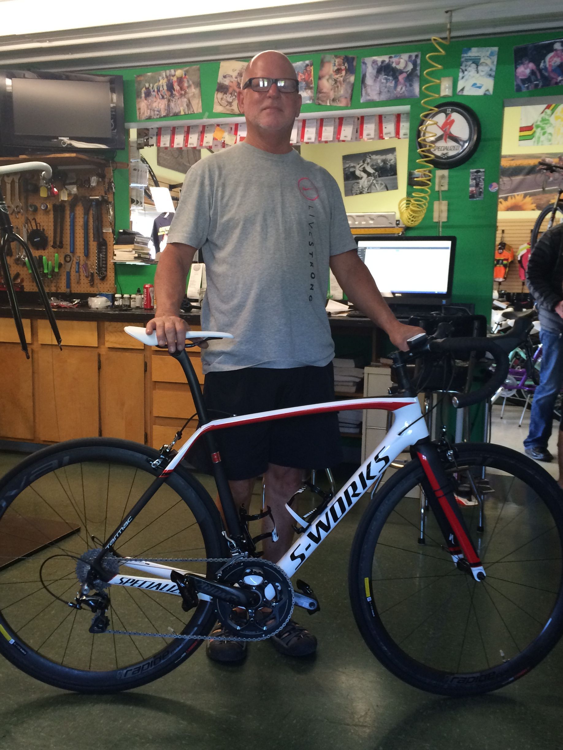 Man standing beside a white road bike inside a bicycle shop