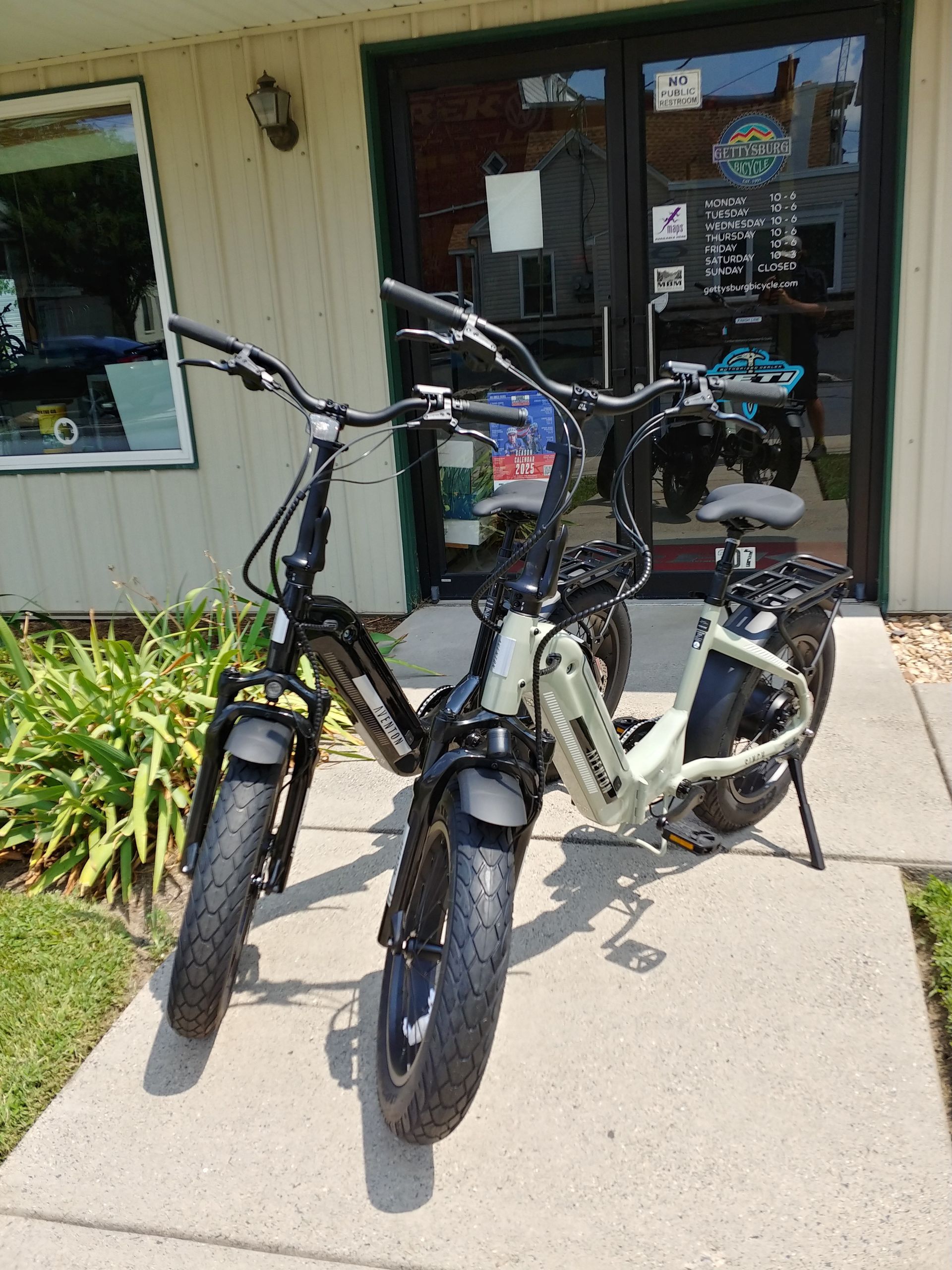 Two electric bikes parked on a sidewalk in front of a building entrance