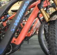 Row of colorful electric mountain bikes, with a matte black and blue frame in the foreground.