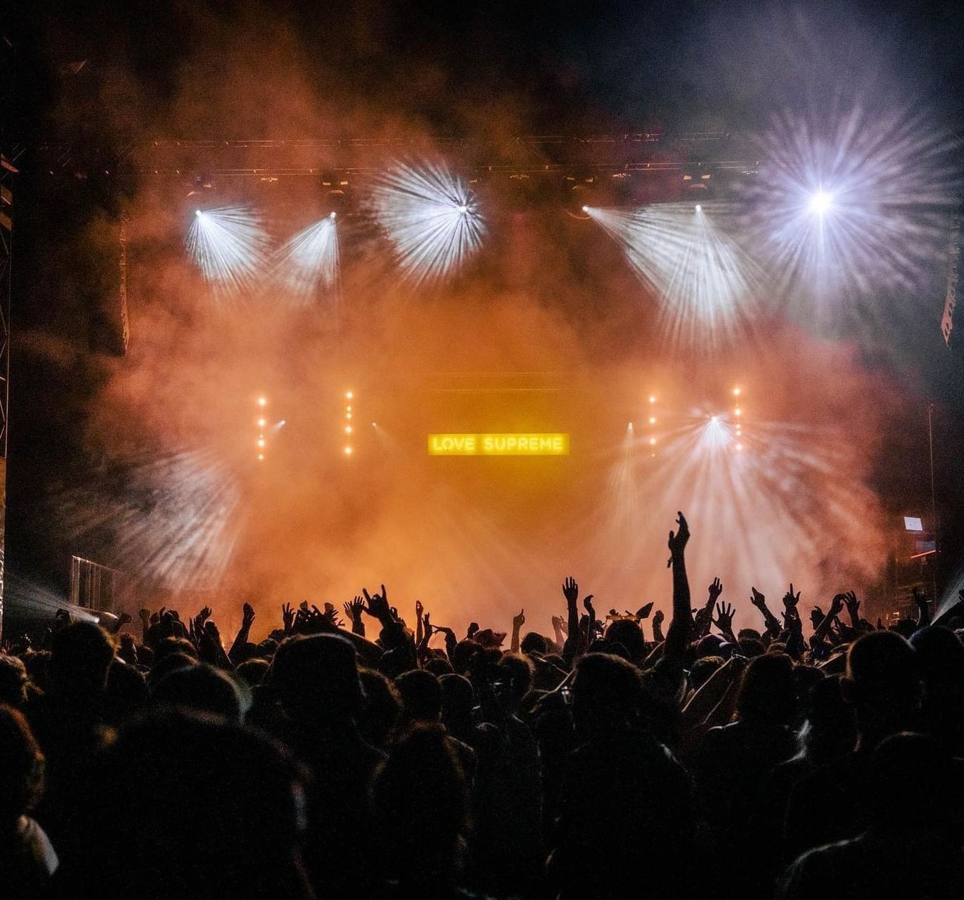 A crowd of people at a concert with their hands in the air