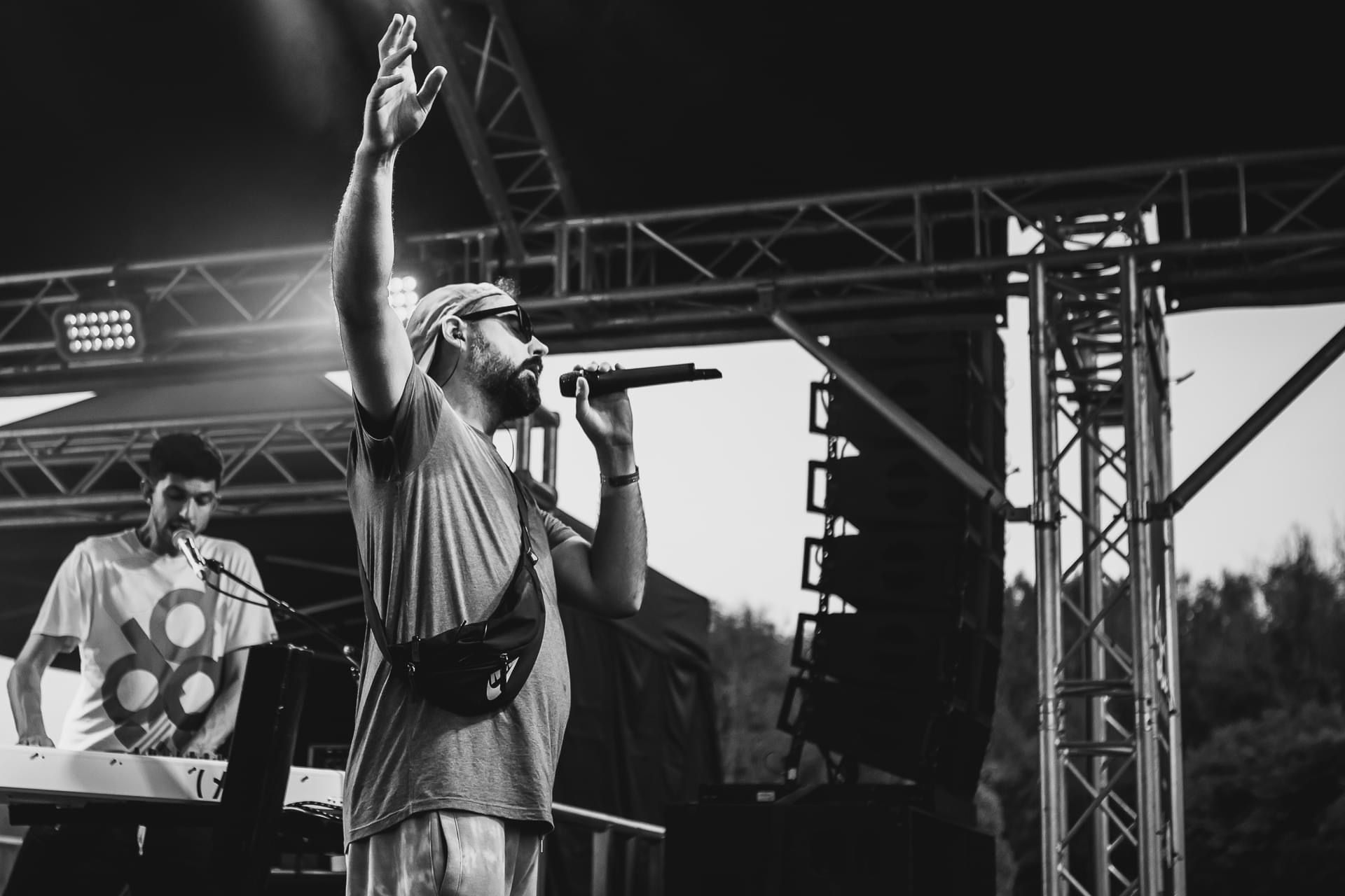 A black and white photo of a man singing into a microphone on a stage.