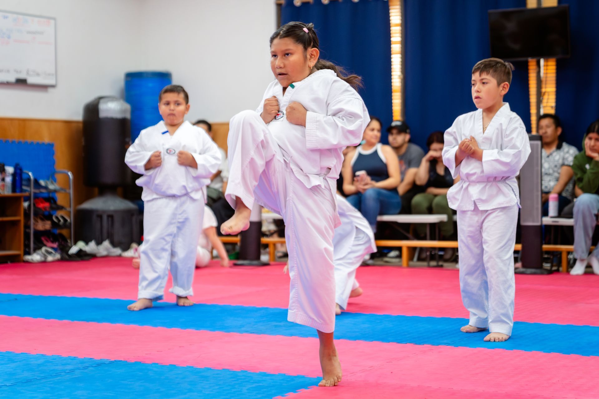 People in uniforms hold large South Korean and American flags in the center of an indoor martial arts arena.