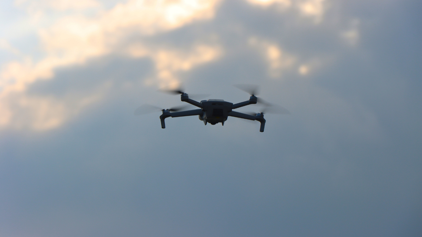 Drone in mid-air against a cloudy sky.