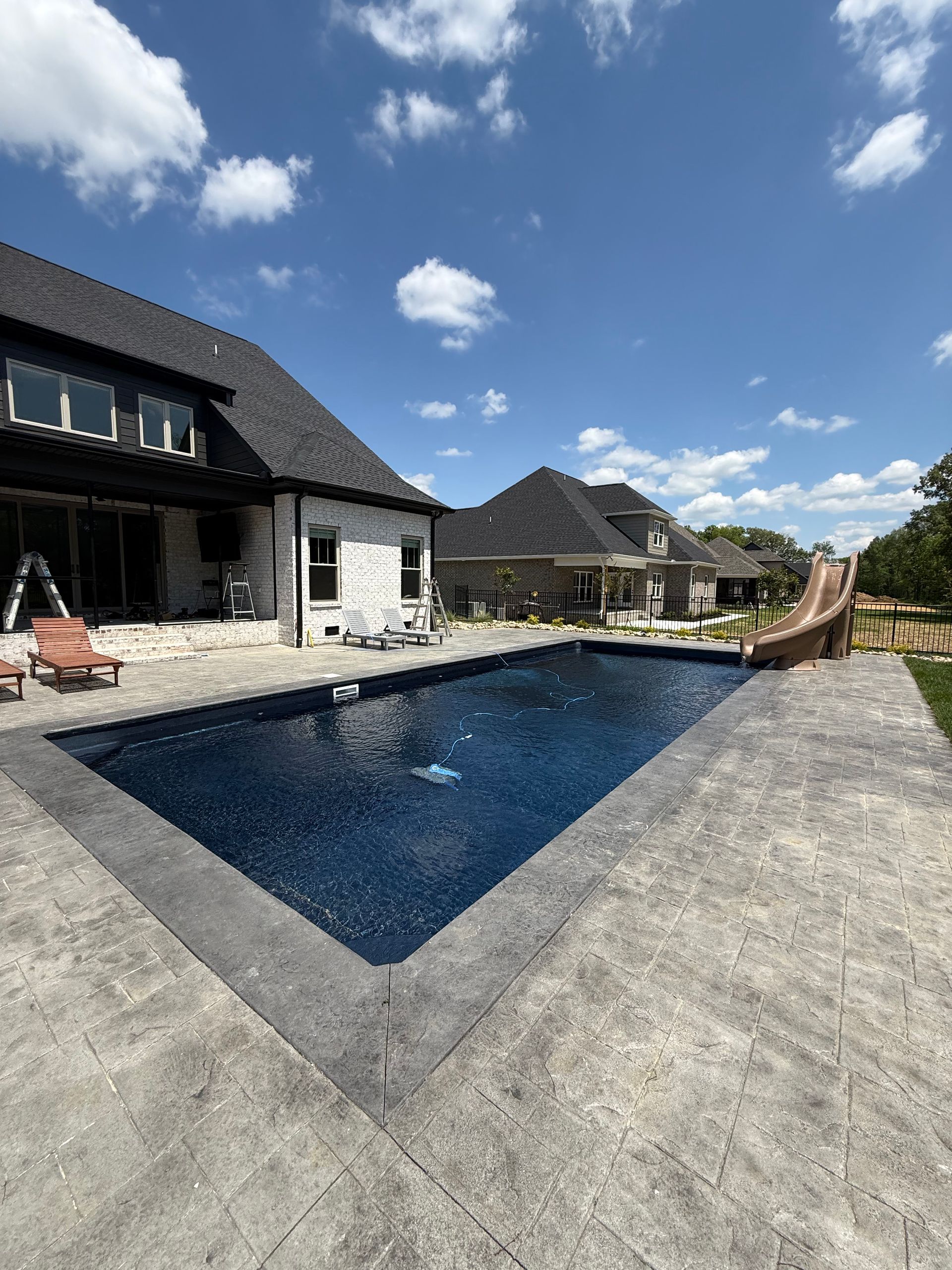 Modern house patio with a rectangular swimming pool under a blue sky