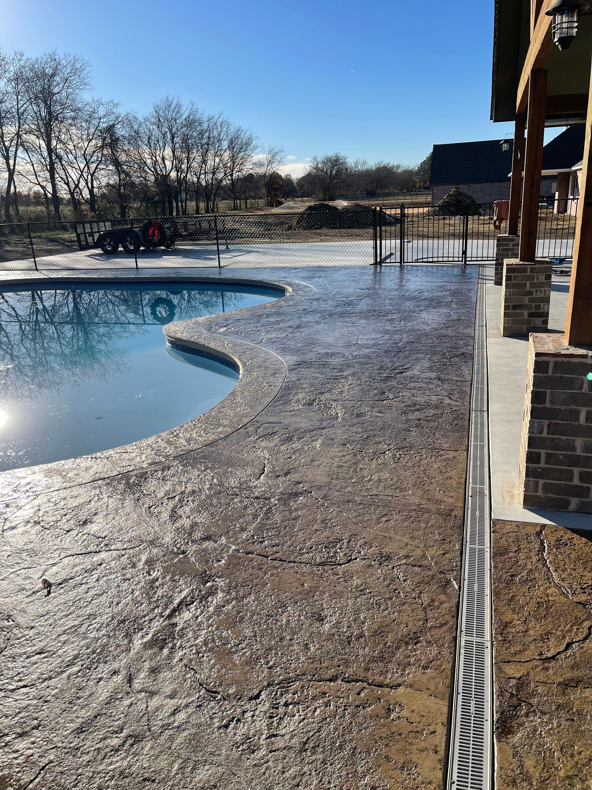 Outdoor pool with icy water and frosty deck beside a building on a sunny winter day
