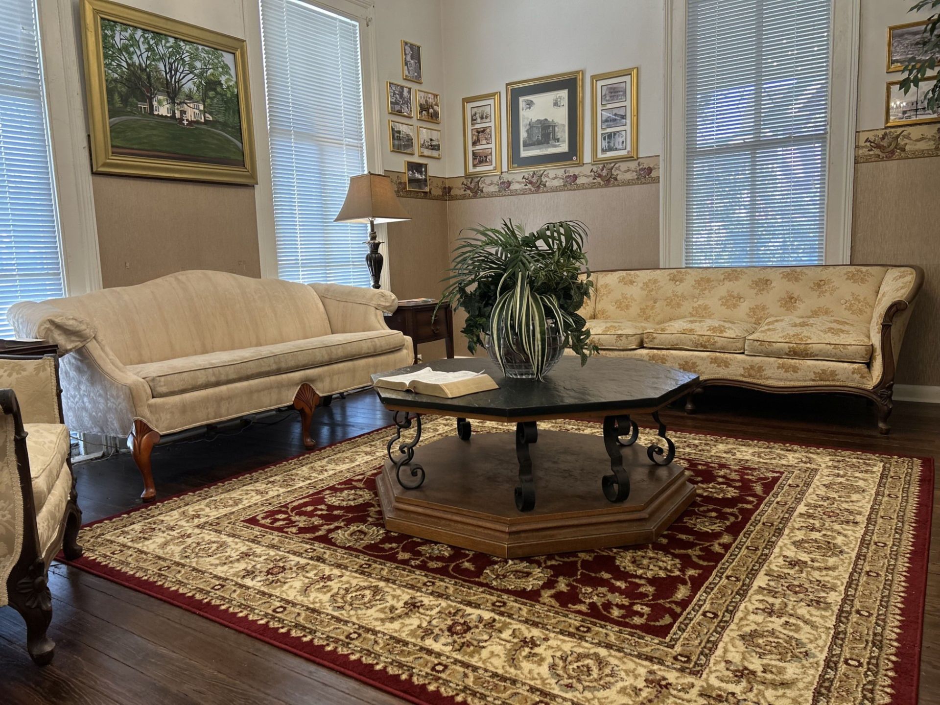Elegant living room with two cream sofas, a round coffee table, and a red patterned area rug