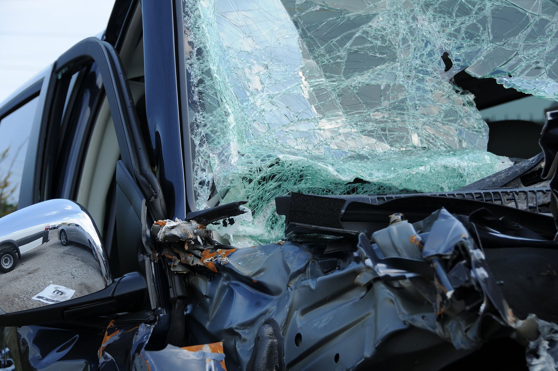 Severely damaged car front with shattered windshield and crumpled hood from a crash